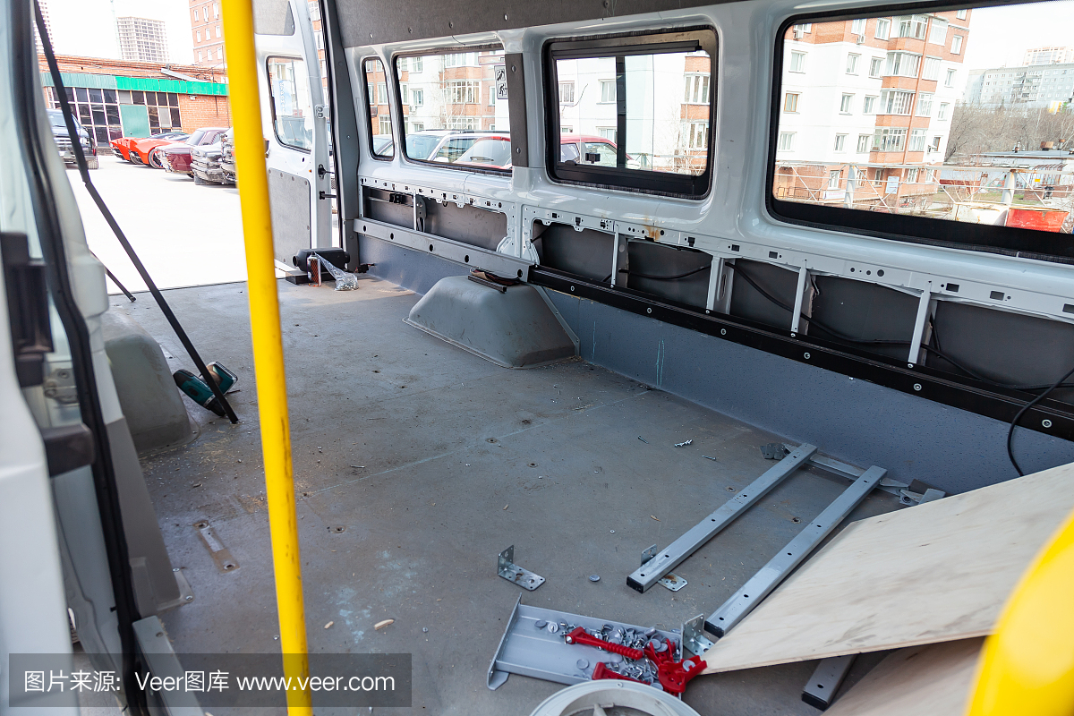 在一辆有大行李厢的货车后部维修和附加设备,在维修过程中,在带有窗户和三个座位的车内去除外壳。